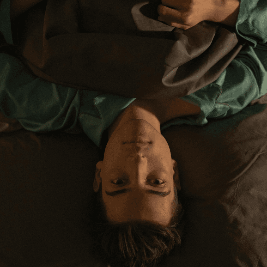 Person lying awake with a busy mind, representing rumination before journaling support.
